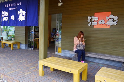 沼の家でだんごを食べている女性