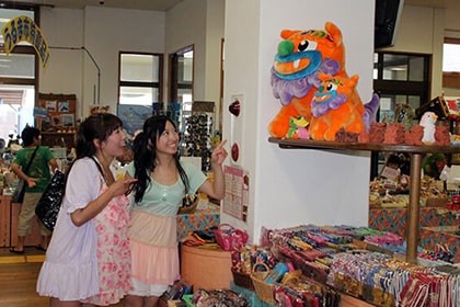 シーサーのぬいぐるみを指す女性たち