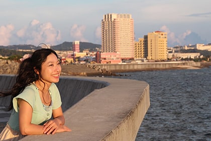 堤防で夕日を眺める女性